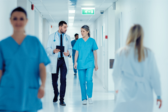 Doctor and nurse walking together down hallway of a hospital